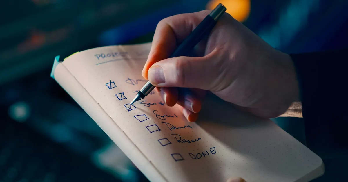 A hand ticking off items on a handwritten checklist