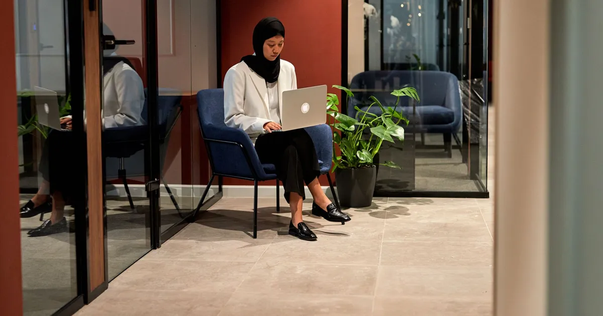 A compliance professional working on a laptop in a quiet, contemporary office